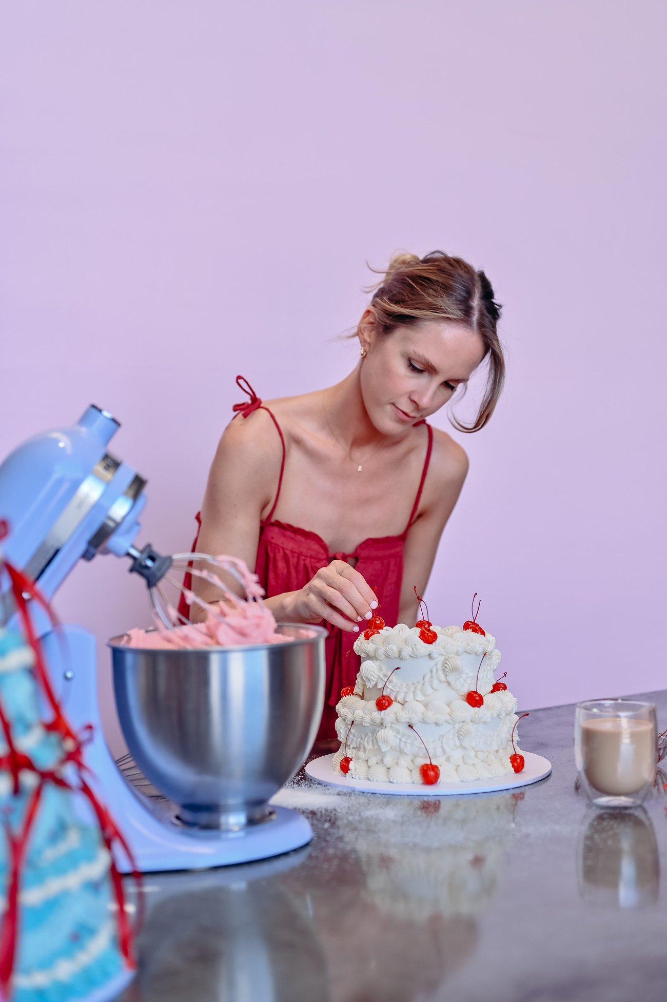 Alyce decorating a white cake topped with cherries